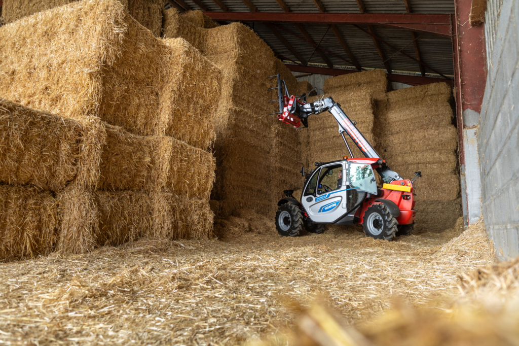 Chariot télescopique électrique Manitou MLT 625e manipulant des bottes de foin dans une grange agricole